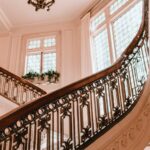 Ornate wooden bannister on a staircase, looking up at light coming through windows in an old home
